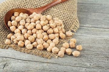 Dried chickpeas in wooden spoon on wooden table. Heap of legume chickpea. Healthy and natural...