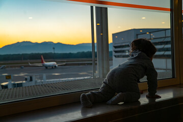 Child crawling on the window sill of the airport window indoors