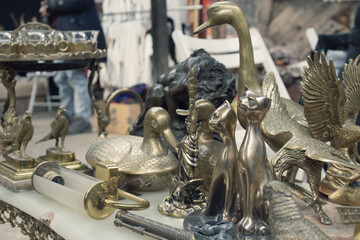 Antiques on flea market or festival - vintage silver and cooper statuettes and other vintage things. Collectibles memorabilia and garage sale concept. Selective focus