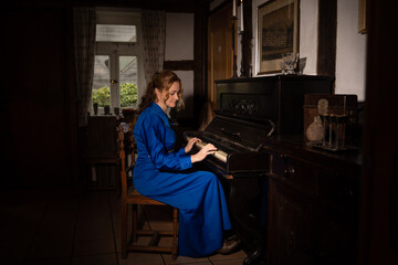 Eine Frau in 18, Jahrhundert im blauen Kleid und langen blonden Haaren spielt Klavier, Es ist...