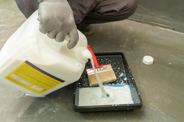 A male builder is priming a wall before further construction work.
