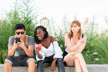 Friends checking mobile phones sitting in a park