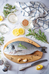 Raw fresh dorada fish with lemon slices and greens