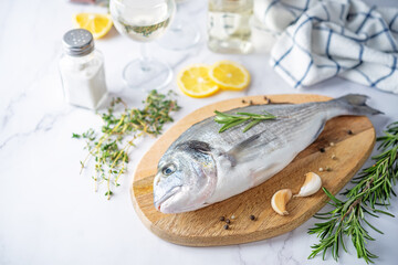 Raw fresh dorada fish with lemon slices and greens