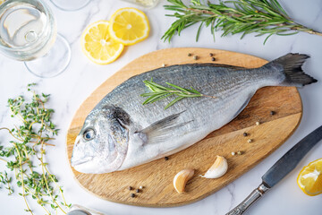 Raw fresh dorada fish with lemon slices and greens