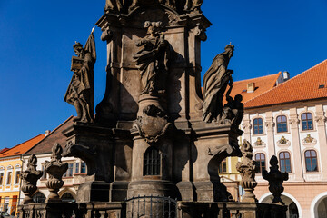 Fototapeta na wymiar Holy Trinity Column with baroque sculptural group, Main town Peace square, Medieval narrow street, gothic and renaissance historical buildings, sunny day, Kadan, Czech Republic