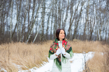 An attractive girl in traditional clothes walks in the winter forest
