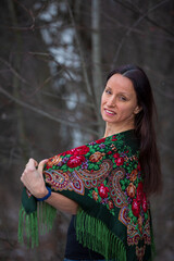 An attractive girl in traditional clothes walks in the winter forest