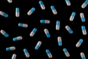 Blue white pills isolated on black background and texture, top view