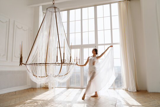 female dancer in white dress near chandelier in the hall