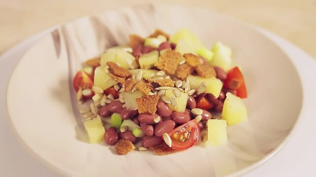 Thai vegetable salad with pineapple and croutons in a plate rotates in a circle