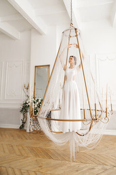 dancer in white dress in a chandelier in a light studio