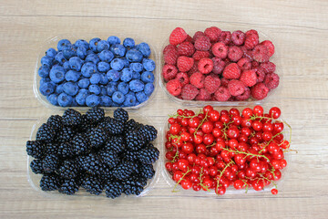 Fresh berries on wooden background, blueberry, raspberry, blackberry and red currant