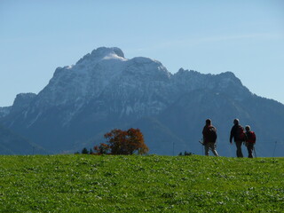 Wanderer auf grünen Wiese zu den schneebedeckten Bergen hin 
