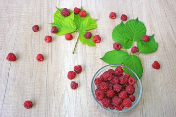 Fresh raspberries on wooden background, close up of berries juicy ripe fruit and leaves
