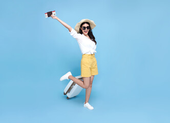 Happy smiling Asian woman dressed in summer clothes with passport and luggage enjoying their summer vacation getaway in blue background.