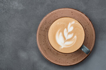 Latte art coffee on grey table. Cup of cappuccino with froth with latte art on grey background. Beautiful dishes.