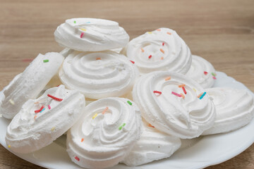Obraz na płótnie Canvas Close-up of white meringues with colored sprinkles
