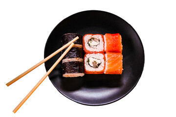 Black plate with seafood: traditional Japanese cuisine dishes sushi snacks on white background. Philadelphia roll with red fish and sushi nori with rice, avocado. Bamboo sticks. East food. Isolated.