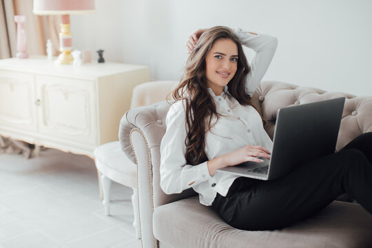 Image of young pleased happy cheerful cute beautiful business woman sit indoors in office using laptop computer 