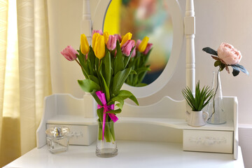 Bouquet of multicolored tulips in a jug on the table in a bright room