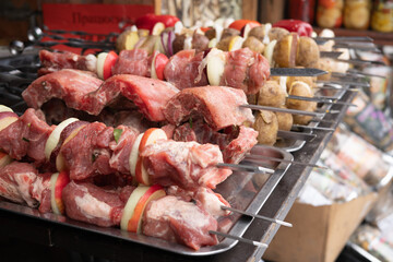 Raw meat and vegetables on skewers are ready for cooking in a street cafe.