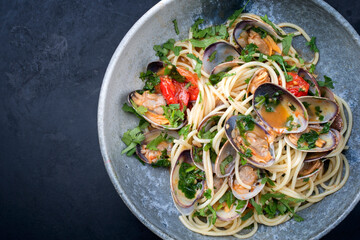 Spaghetti alle vongole with tomato in seafood jus served as top view at a Nordic design bowl with copy space left