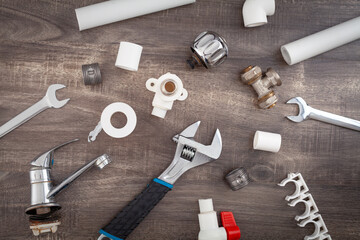Adjustable wrench, plumbers tools and materials on the wooden background.