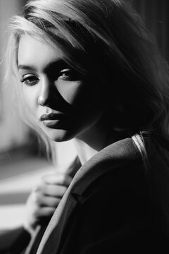 Close up portrait of beautiful young girl in the rays of sun. Shadows on her face. Black and white concept