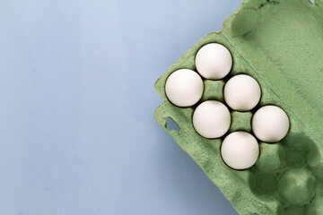 group of white chicken eggs on light blue background with stainless steel whisk , empty space for...