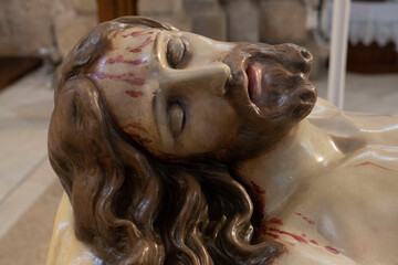 particolare del viso di una statua di Gesù morto  , con gocce di sangue sul viso con espressione sofferente