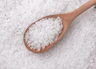 Top view, closeup of coarse salt on a wooden spoon. Food backdrop