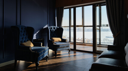 Beautiful interior in front light. Chairs, curtains and panoramic windows. Strong shadow contrast. Selective focus.