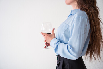 office girl in blue shirt and pearl necklace with glass of wine