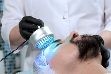 A man doing facial treatments in a cosmetic clinic. Men's cosmetology. Hardware cosmetology....