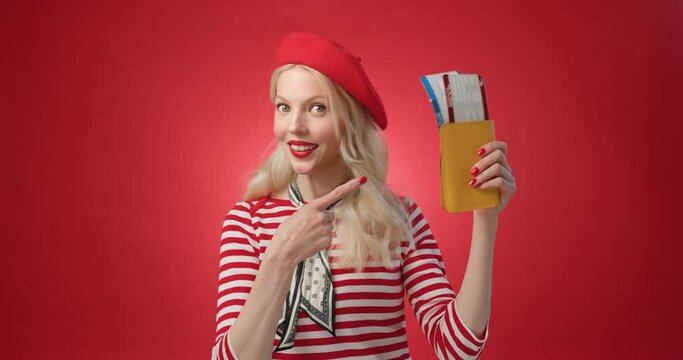 Funny young woman in red beret look at camera waving and happy shows air tickets and gesture fuck off. Trip canceled, fail because lockdown. Isolated red background