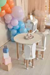 Small table and chairs with bunny ears in children's room interior