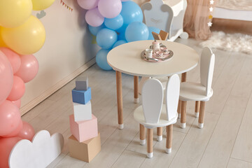 Small table and chairs with bunny ears in children's room interior