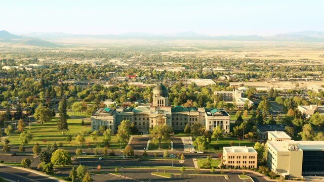 Aerial revealing shot of Helena and Montana State Capitol on a sunny afternoon with hazy sky caused by wildfires. The Montana State Capitol houses the Montana State Legislature.