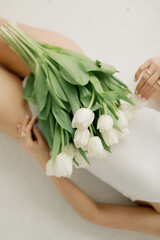 a bouquet of white tulips lies on the hips of a young girl