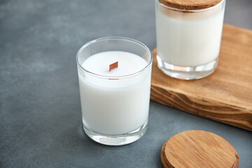 Handmade scented candles in a glass with a wooden lid on a gray background. View from above.