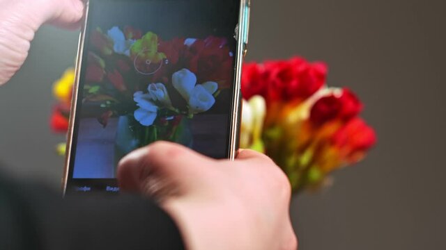 Woman is putting spring flowers in vase. woman's hands taking mobile photo of flower 
