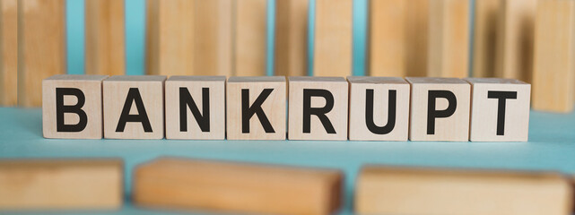 BANKRUPT word written on wooden blocks on light blue background.