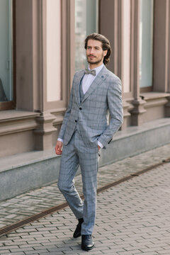 Stylish handsome man with beard, wearing suit jacket and shirt, outdoors on the city street.