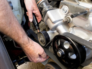 human hands with screwdriver working on an automotive engine