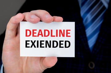 Businessman holding a card with text DEADLINE EXTENDED. Business concept.