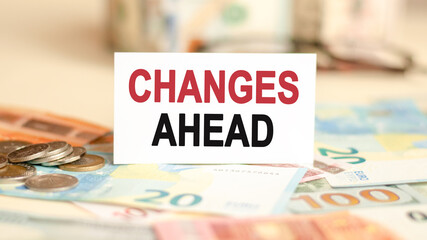 on the table are bills, a coins and a sign on which it is written changes ahead, finance and economics concept