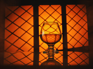 Glass of cognac (whiskey) on a warm orange background