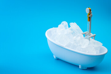 Muscle recovery and healing therapy, performance improvement treatment and extreme cold cryotherapy concept with minimalist bathtub filled with ice isolated on blue background with copy space - 425891684