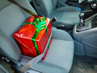 Transportation neatly by car in the passenger seat of a large red birthday present in a beautiful...